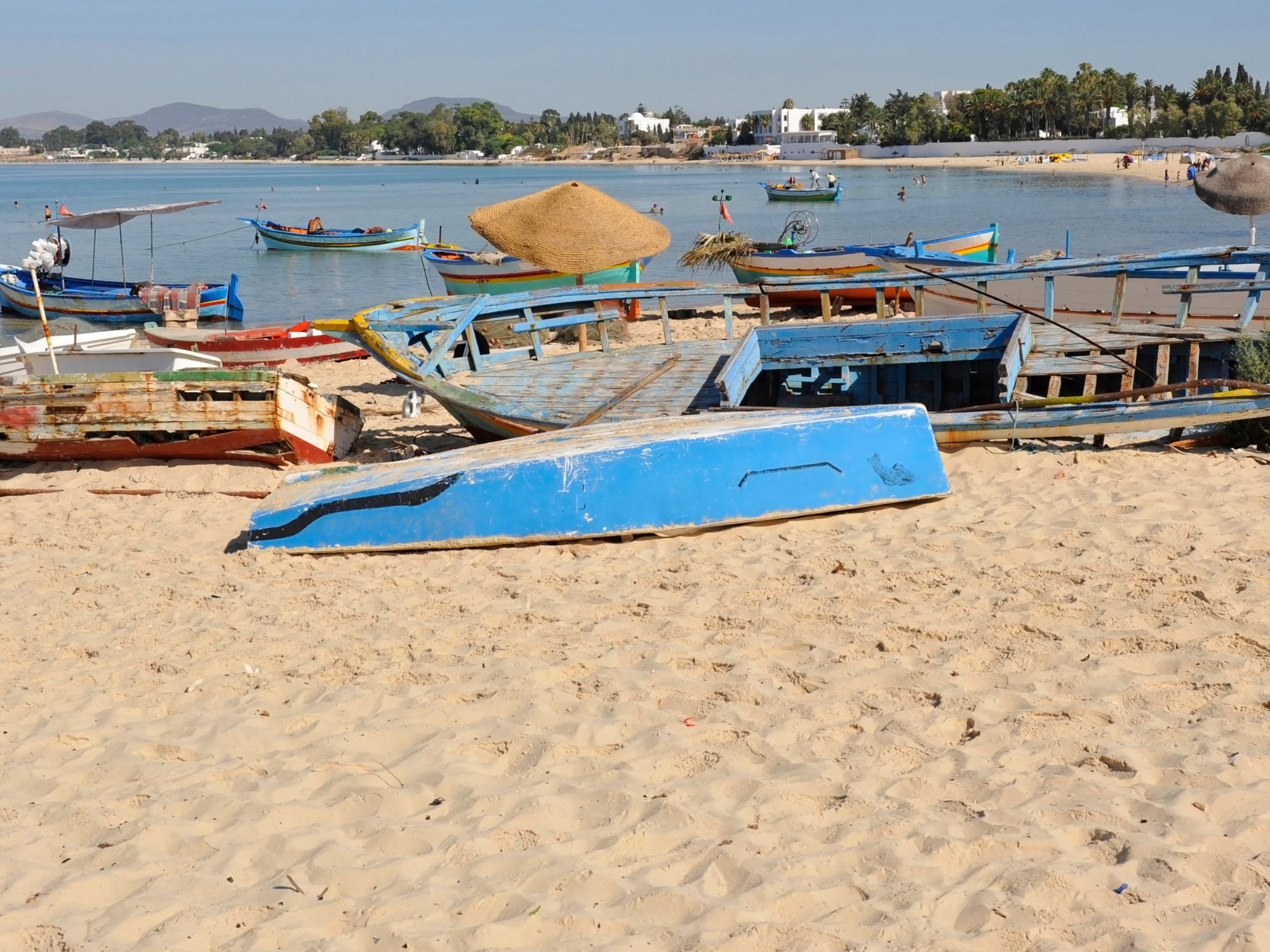 Stranden i Hammamet med farverige både og bjerge i baggrunden. Foto Viktors Farmor