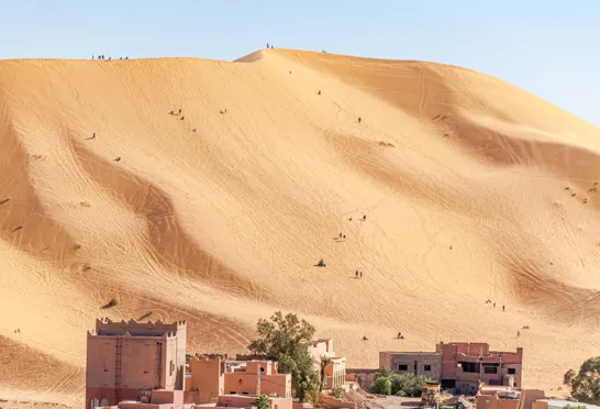 Den enorme sanddune ved Taghit i Algeriet, hvor mennesker ses som små myrer i deres forsøg på at bestige det. Foto Viktors Farmor