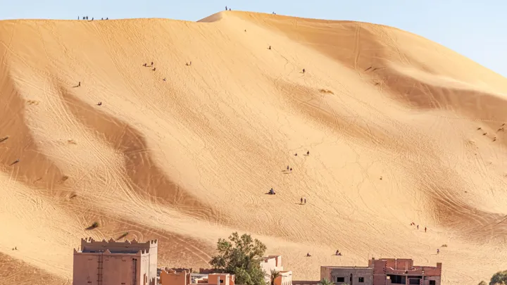 Den enorme sanddune ved Taghit i Algeriet, hvor mennesker ses som små myrer i deres forsøg på at bestige det. Foto Viktors Farmor