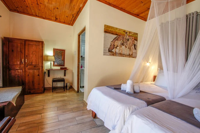 Et roligt og hyggeligt lodge midt i Zululand, omgivet af høje træer og natur. 