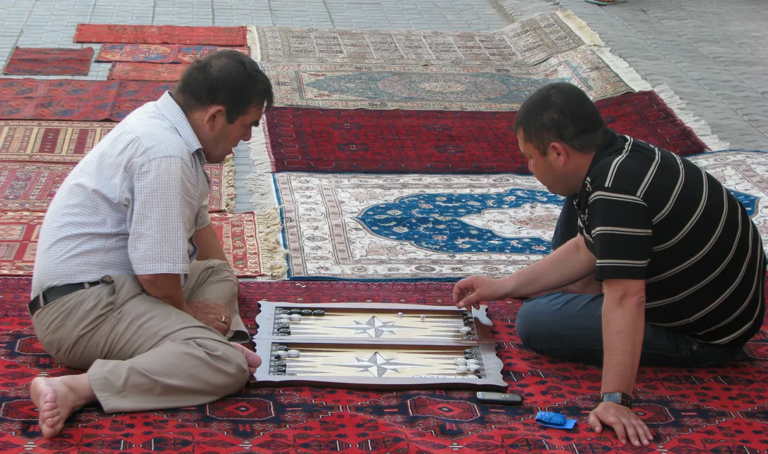Tæppehandleren i Bukhara har tid til et spil, når der ikke er kunder. Foto Vagn Olsen