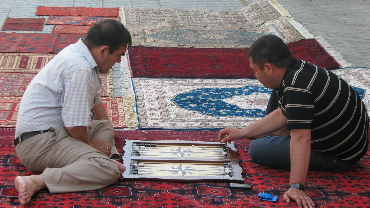 Tæppehandleren i Bukhara har tid til et spil, når der ikke er kunder. Foto Vagn Olsen