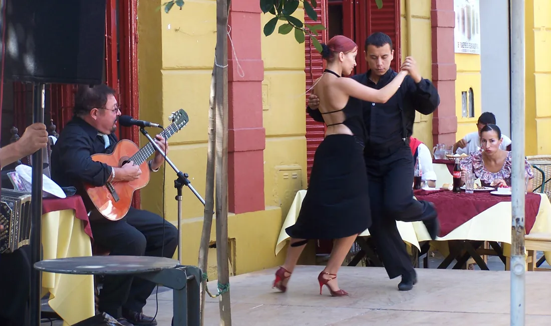 Par danser tango, foran en mand der spiller guitar ved rejse til Argentina.