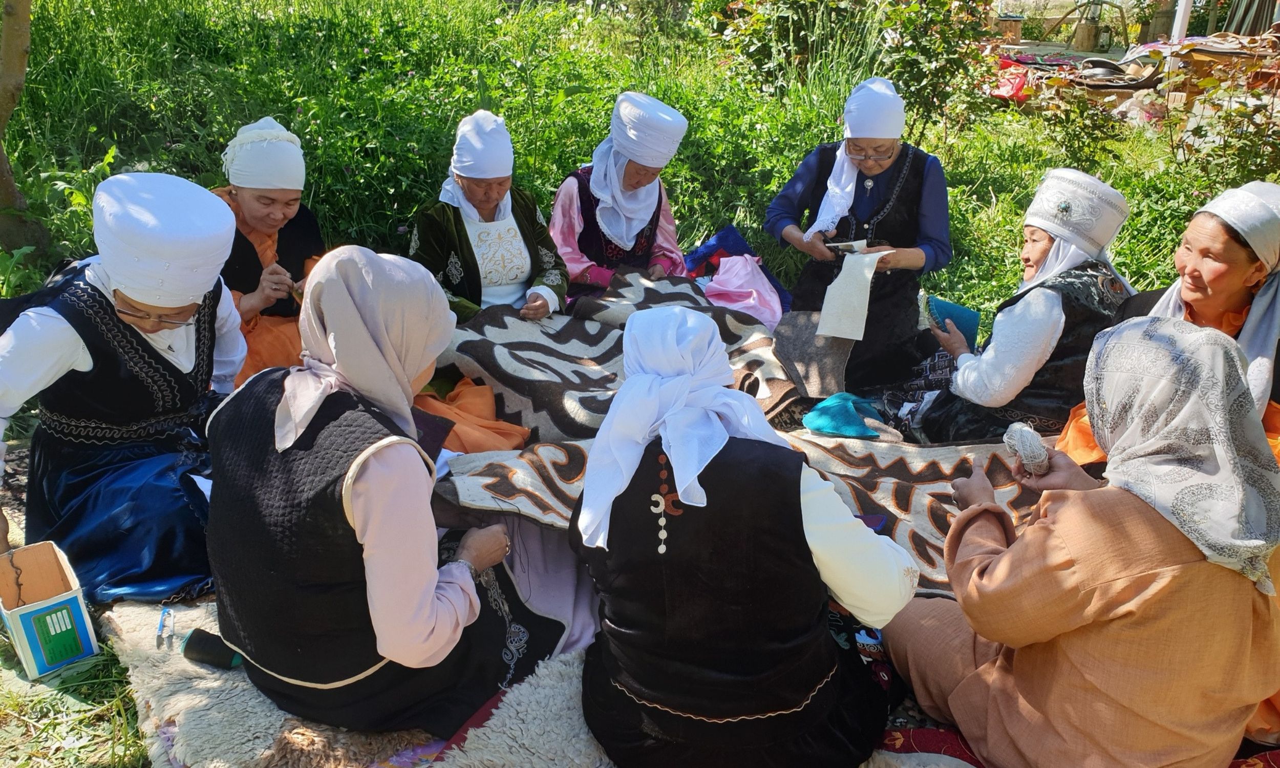 Landsbykvinderne synger, mens de arbejder på et stort filttæppe. Foto Kirsten Gynther Holm
