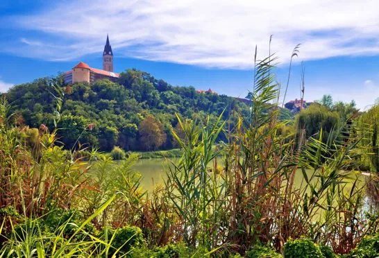  Ilok-kirken troner majestætisk på bakken med udsigt over den søen i Kroatiens idylliske Slavonija-region.Foto Viktors Farmor